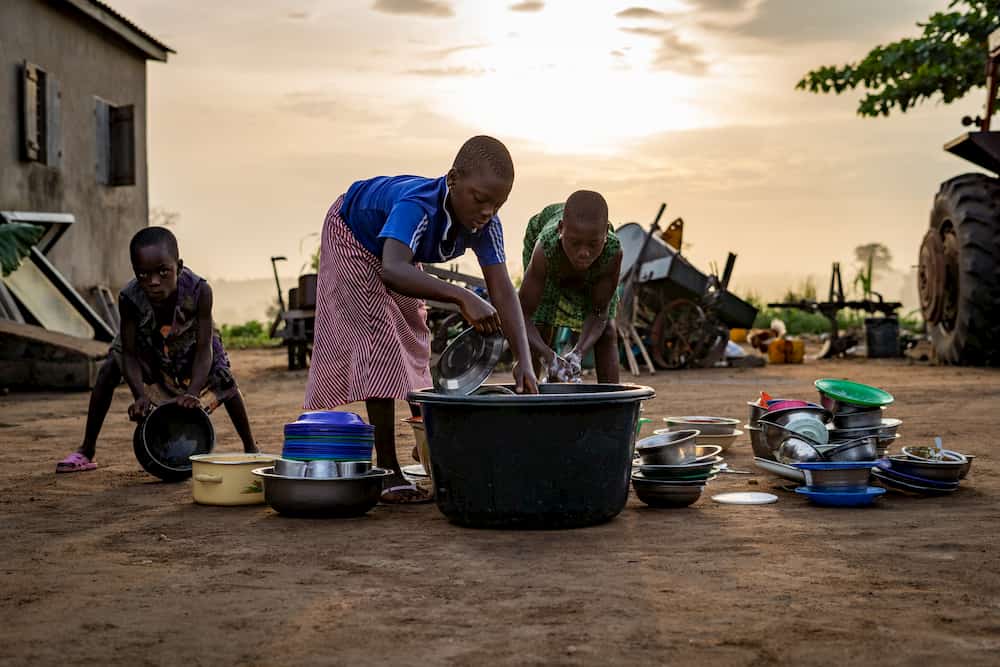 Poor young teenagers are washing clothes on the ground.